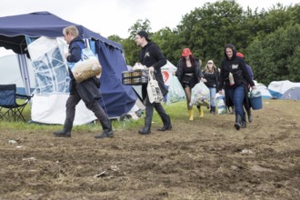 Festival visitors carry their luggage through mud on a campsite at the Rock am Ring festival on