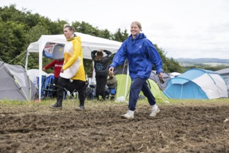 Two festival visitors walk through mud on a campsite at the Rock am Ring Festival on Saturday,