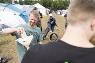 Festival visitors drinking from a funnel on a campsite at the Rock am Ring Festival on Saturday,
