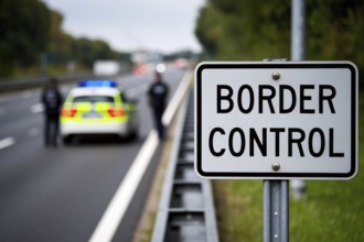 White road sign saying 'Border control' with blurry police car and offecers in background, AI