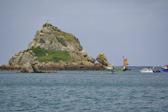 Boats in the sea near a small rocky island under a blue sky, Tresco, Isles of Scilly, Cornwall,