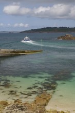 Small boat sailing through a rocky inlet on the way to the open sea, St Agnes, Isles of Scilly,