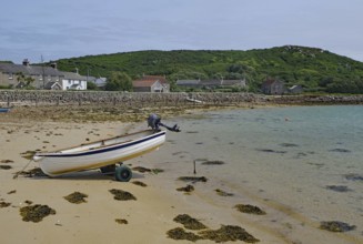 Small boat on a trailer on a quiet sandy beach near residential houses, Tresco, Isles of Scilly,