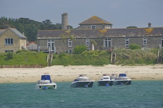 Four small boats close to the beach in front of traditional houses in an idyllic setting, Tresco,
