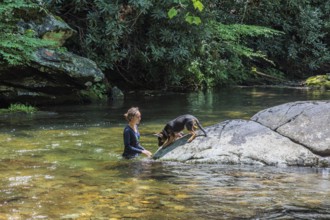 Young woman and her German Shepard dog playing in the Hiawassee River flowing through the Fires