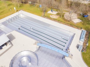 Aerial view of an empty outdoor pool with swimming pool and surrounding lawn in autumnal
