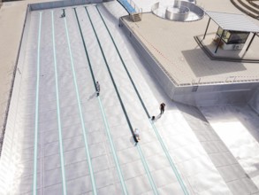 High-angle shot of a swimming pool under construction with workers, renovation of the swimming