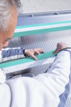 Worker adjusts stripes in the swimming pool with his hands, renewal of the swimming lines, Calw