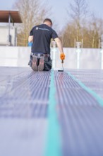 A worker kneels and works with tools on pool tiles, renovation of the swimming lines, Calw