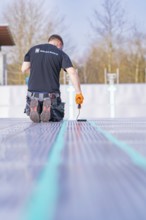 Rear view of a worker on a construction site applying strip paint with a roller, renovation of the