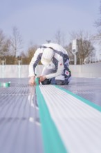 A worker on the construction site sticks a green tape along the floor, renewal of the swimming