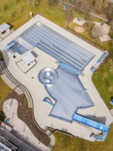 Aerial view of the entire swimming pool area with water slides and green areas, renovation of the