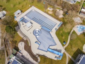 Spacious aerial view of a swimming pool with green areas and several buildings, renovation of the