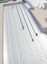 Close-up of the swimming lanes with three people in the empty pool area, renovation of the swimming