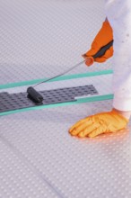 Close-up of a gloved hand using a paint roller on the floor, renovation of the swimming lines, Calw