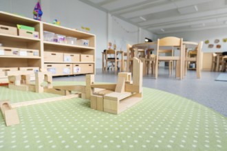 Large play area in the kindergarten with wooden floors and building blocks, transitional