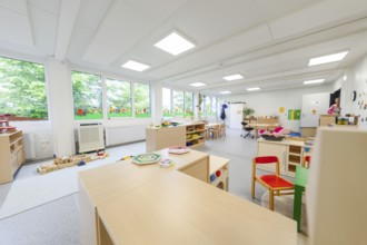 Large, open kindergarten room with windows and child-friendly furniture, transitional containerised