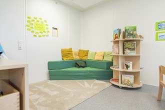 Cosy reading corner in a kindergarten with colourful cushions and books, transitional daycare
