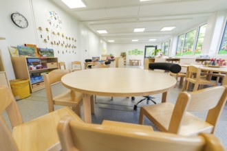 Kindergarten room with round table, wooden furniture and toys, bright atmosphere, transitional