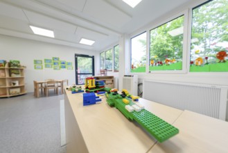 Kindergarten room with building blocks on a table, large windows with a view of the countryside,