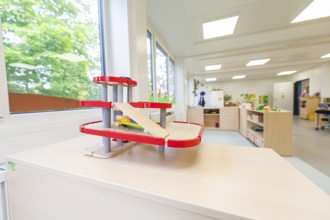Kindergarten room with a red race track for toy cars and large windows, transitional containerised