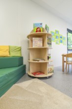 Children's room with bookshelf and sofa, colourful cushions and decorative pictures on the wall,