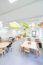Open school classroom with paper artwork and wooden furniture, transitional containerised daycare