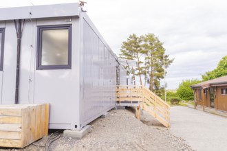 Exterior view of a grey modular building with trees in the background, transitional daycare centre
