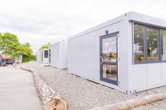 Plain grey containers in an area surrounded by trees, transitional daycare centre in container