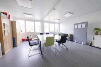 Modern meeting room with chairs around a table, large windows create light, transitional daycare