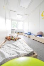 Sleeping room for children with beds and colourful cushions, flooded with light and quiet,