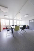 Bright meeting room with various chairs and table in a modern style, transitional daycare centre in