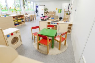 Children's room with colourful chairs and a small play kitchen on carpet, transitional daycare