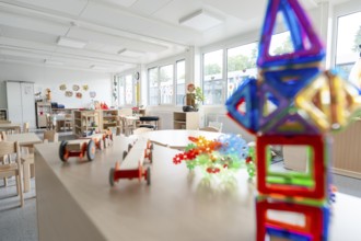 Colourful kindergarten room with toys and large windows, flooded with light, transitional