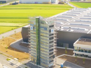 Industrial building with scaffolding and solar panels, surrounded by green fields, ING Park