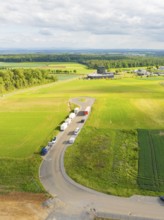 Country road with parked vehicles and extensive fields in a rural setting, ING Park development