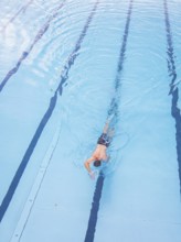 A man swims in the clear blue water of a pool along the lanes, Calw outdoor pool, Black Forest,