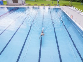 A swimmer moves alone through the lanes of a large swimming pool, Calw outdoor pool, Black Forest,