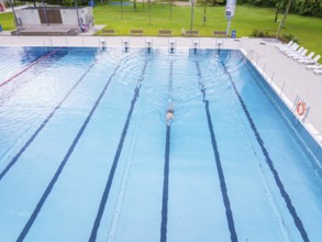A swimmer swimming his laps in a large, empty swimming pool, Calw outdoor pool, Black Forest,