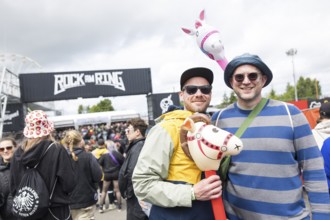 Two festival visitors with their inflatable animals Charles and Chantal in front of a container