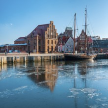 Winter in the Old Harbour with historic sailing ship, ice on the water, brick architecture of