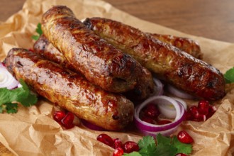 Fried kupaty on parchment, with red onion and pomegranate, kupaty, Georgian cuisine