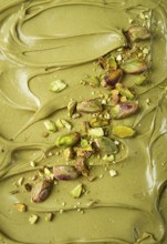 The texture of pistachio paste, with pistachios and crumbs, full frame, close-up