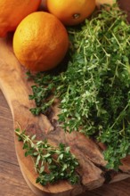 Lemon thyme, on a wooden chopping board, with lemons, close-up