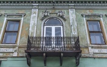 Dilapidated 19th century house with sculptures above the rusty balcony, Medias, Romania