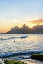 Surfing on Ipanema beach in Rio de Janeiro during sunset with the Two Brothers hill in the