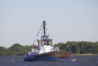 Decorated ship type Fairplay-91 tugboat leaves the port of Hamburg on the Elbe after Hamburg's port