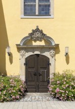 Side portal with sandstone decorations and blooming rose bushes at the town church of St. Nicolai