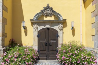 Side portal with sandstone decorations and blooming rose bushes at the town church of St. Nicolai