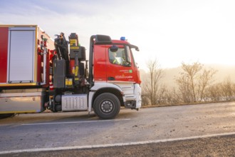 Fire engine on the road towards sunrise, landscape in the background, fire department exercise on